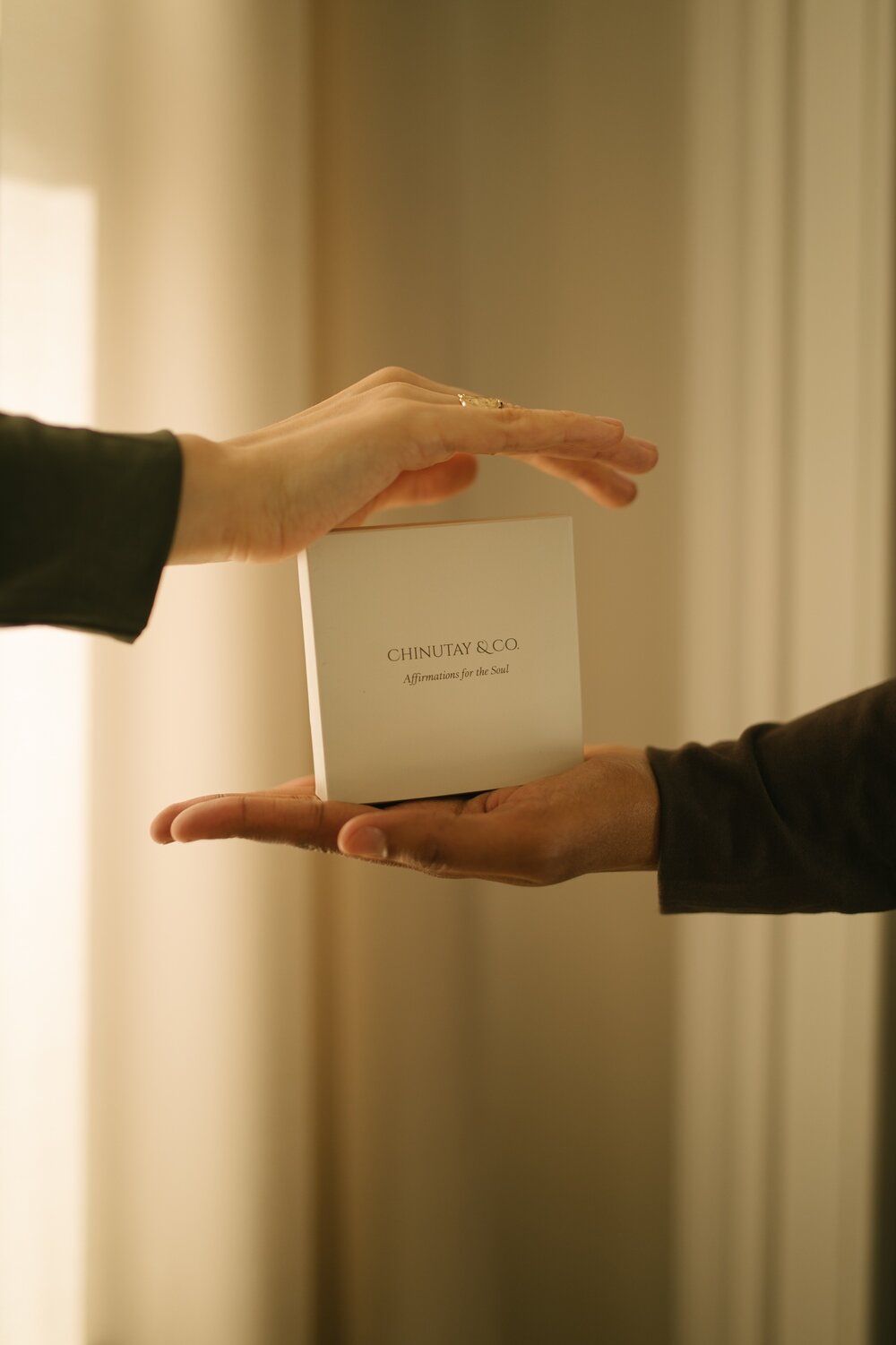Two hands holding a box of Chinutay & Co daily positive affirmation cards.